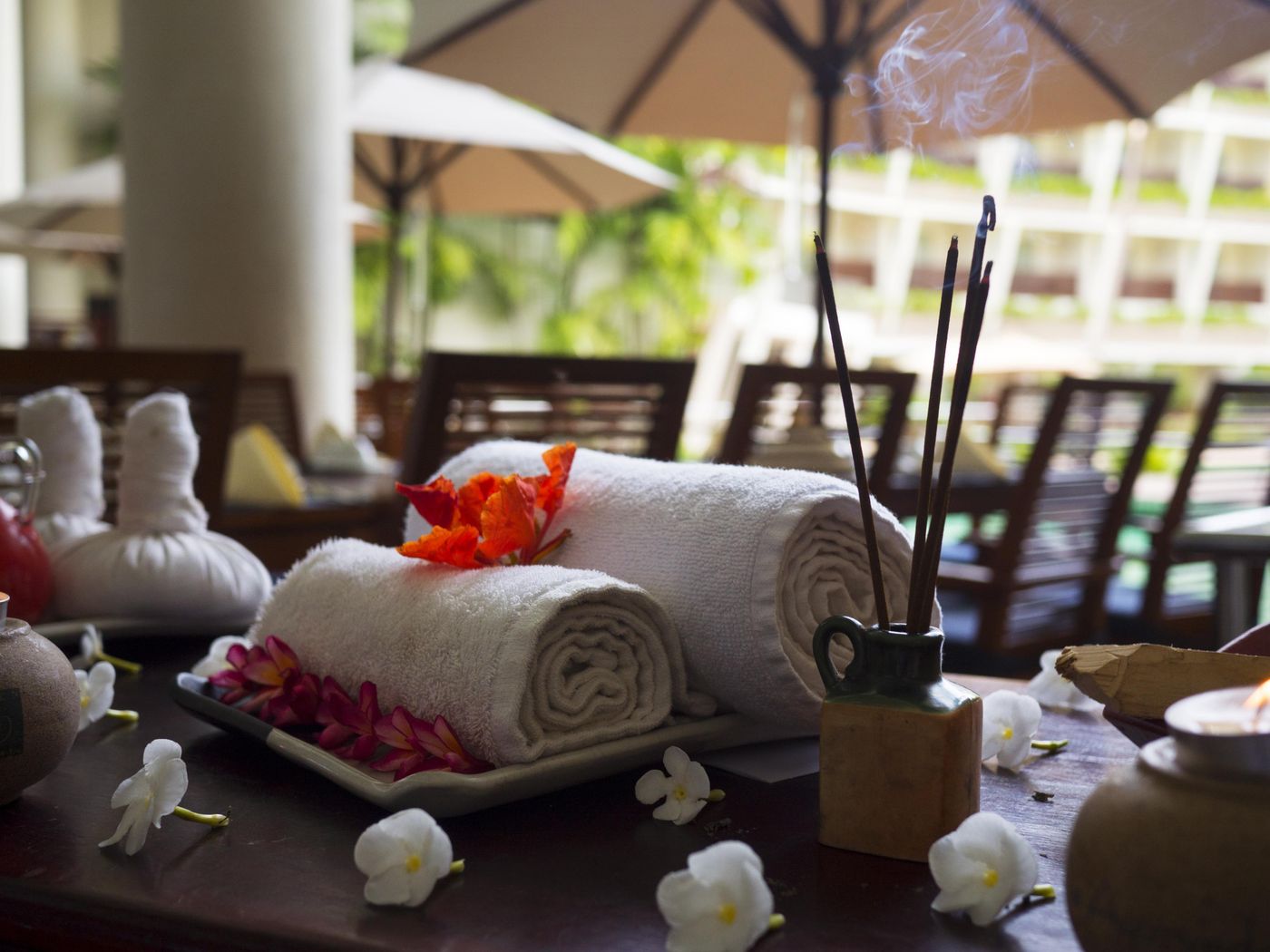 Rolled spa towels, incense and flowers in warm light